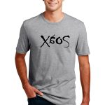 Man wearing a gray T-shirt with the text "Xéos" in black, standing with hands in pockets, smiling at the camera. White background.