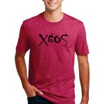 A person wearing a maroon T-shirt featuring the text "Soxé" in a stylized font. They are standing with hands on sides against a plain white background, smiling, and wearing dark jeans.