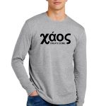 Young man wearing a gray long-sleeve shirt with the word "xáos" and the phrase "CREATE SOME." printed in black. He has curly hair and blue jeans, standing against a plain white background.